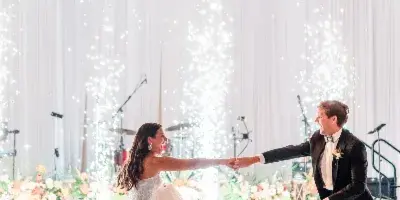 A bride and groom dancing at a wedding reception under large decorative chandeliers.