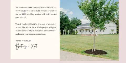 Exterior view of a white barn wedding venue with a covered patio, lawn, and trees.