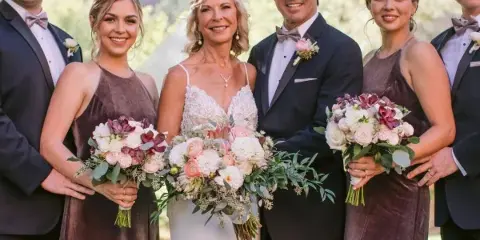 A wedding party posing with floral bouquets and boutonnieres in front of Sedona red rocks.