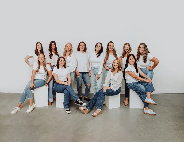 A group of ten women, the wedding coordination team, posing together in a studio setting.
