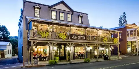 Exterior view of the historic Hotel Sutter building at dusk, showing the two-story structure with a balcony and signage.