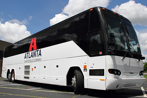 A white and black charter bus with Atlanta Charter Bus Company branding parked outdoors.