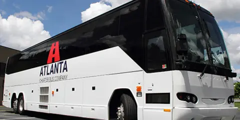 A white and black charter bus with Atlanta Charter Bus Company branding parked outdoors.