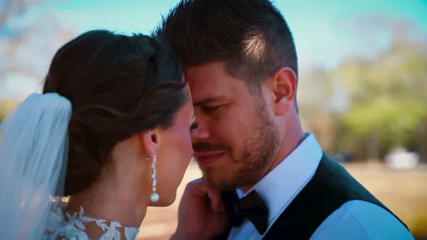 A close-up photograph of a bride and groom sharing an intimate moment, with the bride wearing a veil and the groom in a suit and bow tie.
