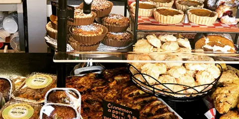 A display case at Mimi's Plate filled with various baked goods, pies, and pastries, including cinnamon rolls and pumpkin cake.