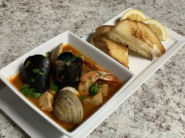 Plated seafood stew with mussels, clams, shrimp, and bread