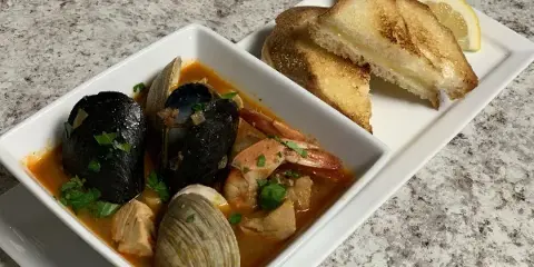 Plated seafood stew with mussels, clams, shrimp, and bread