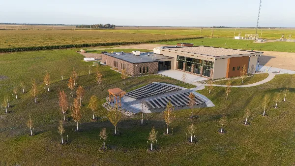 Aerial view of a modern event venue building with outdoor seating area and landscaped grounds in a rural setting.