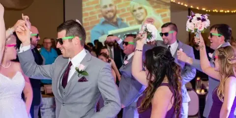 Wedding reception dance floor with the couple and guests dancing under event lighting.