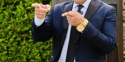 A man in a blue suit and tie pointing at the camera.
