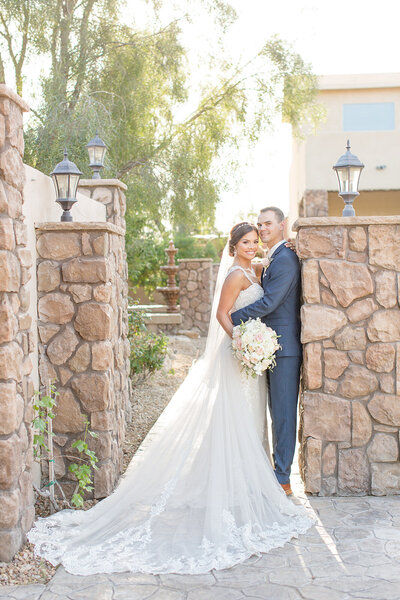 A bride and groom standing together in a stone courtyard at a wedding venue.