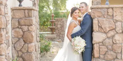 A bride and groom standing together in a stone courtyard at a wedding venue.