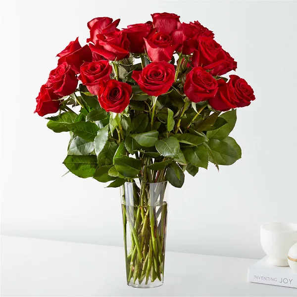 A bouquet of long-stem red roses arranged in a clear glass vase.