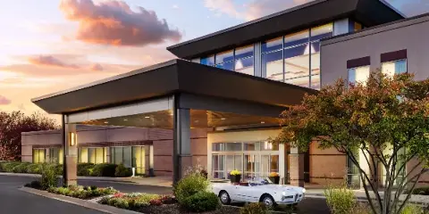 Exterior view of the Eaglewood Resort & Spa building at dusk with a white classic car parked at the entrance.