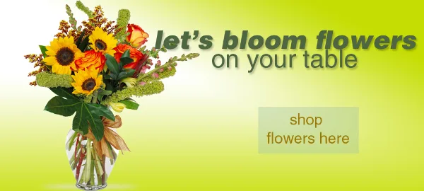 A vase containing a colorful bouquet of sunflowers, orange roses, and greenery.