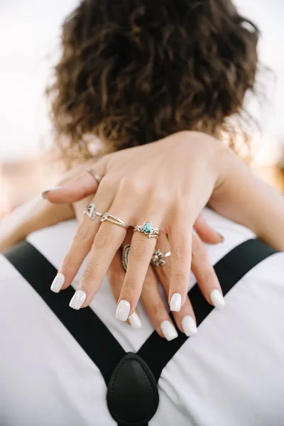 Close-up of a couple's hands showing wedding rings and manicured nails.