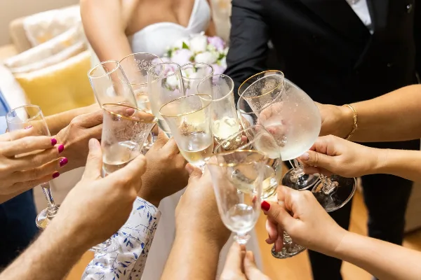 A group of people, including a bride and groom, raising champagne flutes in a toast at a wedding reception.