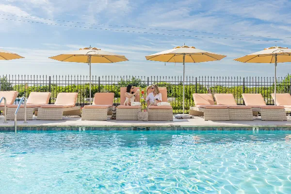 Outdoor swimming pool with lounge chairs and umbrellas at a beachfront resort.