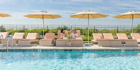 Outdoor swimming pool with lounge chairs and umbrellas at a beachfront resort.