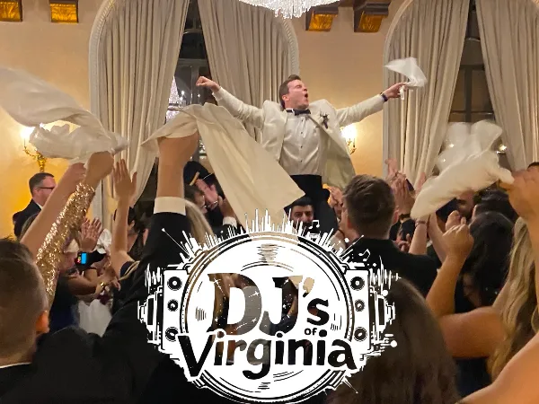 A groom in a white tuxedo is lifted onto a guest's shoulders during a wedding reception dance, with the DJ's of Virginia logo overlaid.