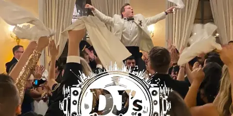 A groom in a white tuxedo is lifted onto a guest's shoulders during a wedding reception dance, with the DJ's of Virginia logo overlaid.