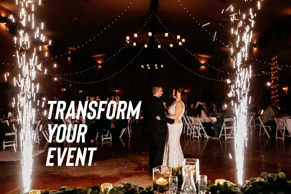 A bride and groom dancing at a wedding reception with sparkler effects and string lights.