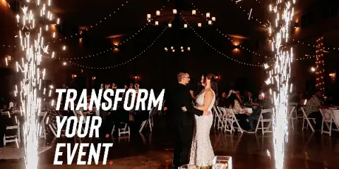 A bride and groom dancing at a wedding reception with sparkler effects and string lights.