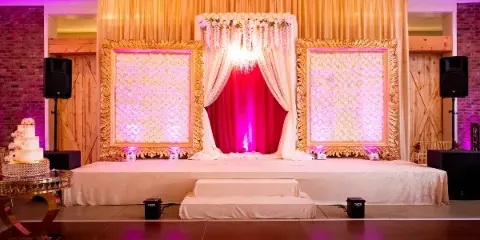 A decorated wedding stage featuring a dance floor, floral arch, and ornate gold frames.