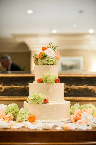 Three-tier wedding cake decorated with orange and pale green flowers