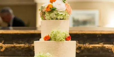 Three-tier wedding cake decorated with orange and pale green flowers