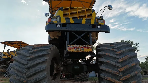A large yellow and black monster truck with oversized tires parked outdoors.