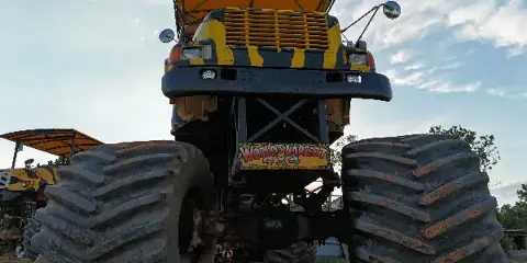 A large yellow and black monster truck with oversized tires parked outdoors.