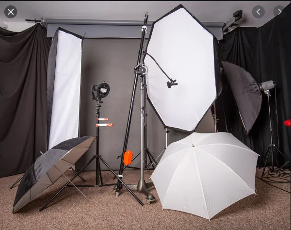 Professional studio lighting equipment including softboxes, umbrellas, and light stands arranged in a production space.