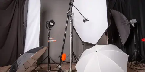Professional studio lighting equipment including softboxes, umbrellas, and light stands arranged in a production space.