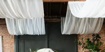 Wedding couple kissing during a ceremony in an industrial venue with exposed brick walls and white drapery.