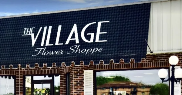 Exterior of The Village Flower Shoppe storefront with brick facade and window display