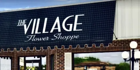 Exterior of The Village Flower Shoppe storefront with brick facade and window display