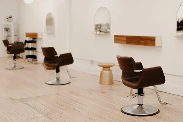 Bright salon interior with brown styling chairs, mirrors, and light wood flooring.