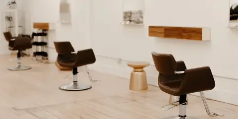 Bright salon interior with brown styling chairs, mirrors, and light wood flooring.