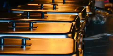 A row of stainless steel chafing dishes set up for a catering event.