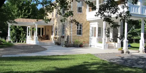 Exterior view of the Oldenburg House, a historic brick building with white porches and a grassy lawn.