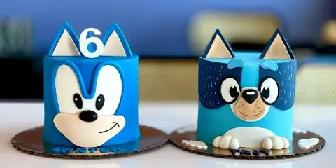 A custom blue cake decorated with a cartoon character face and the number 6.