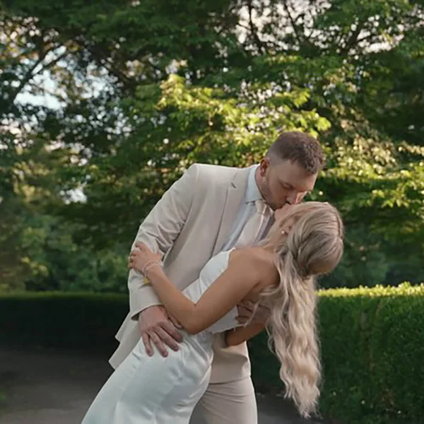 A bride and groom sharing a kiss in an outdoor garden setting.