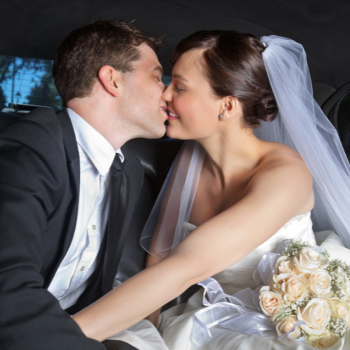 Bride and groom sharing a kiss in the back of a luxury limousine