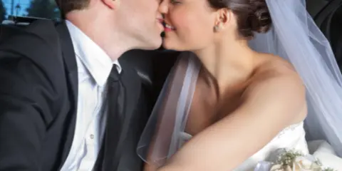 Bride and groom sharing a kiss in the back of a luxury limousine