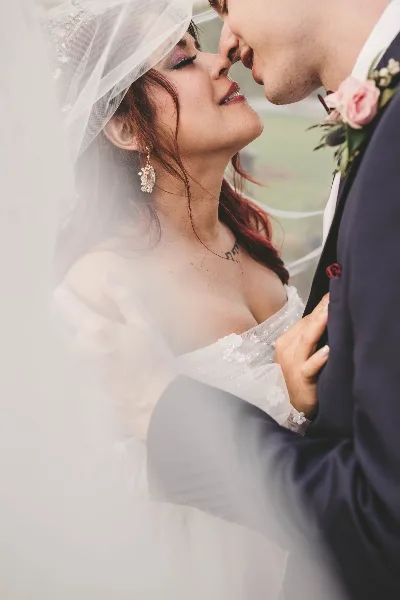 A close-up portrait of a bride and groom sharing a tender moment, with the bride wearing a veil and the groom in a suit.