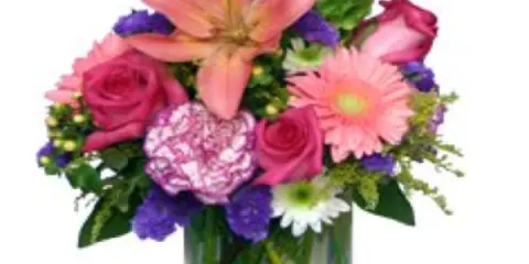 A vibrant floral arrangement featuring pink lilies, roses, and carnations in a clear glass vase.