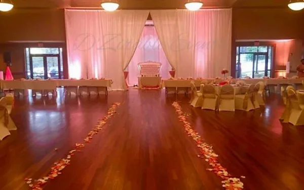 A wedding reception hall with set tables, chairs, and a floral aisle.