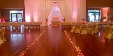 A wedding reception hall with set tables, chairs, and a floral aisle.