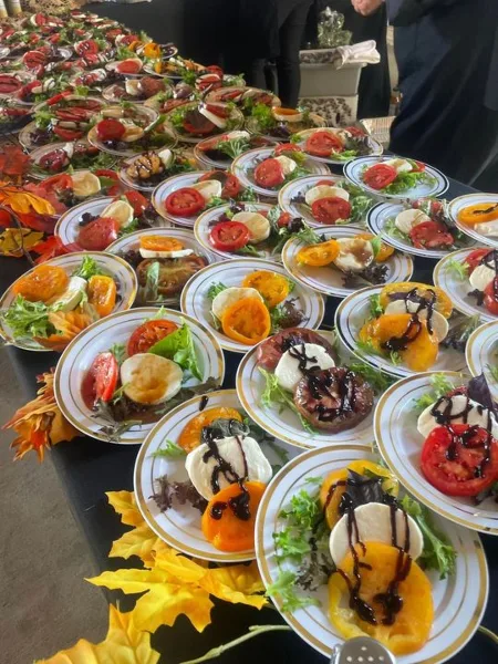 A long table filled with numerous plates of bruschetta appetizers, garnished with balsamic glaze and fresh vegetables.